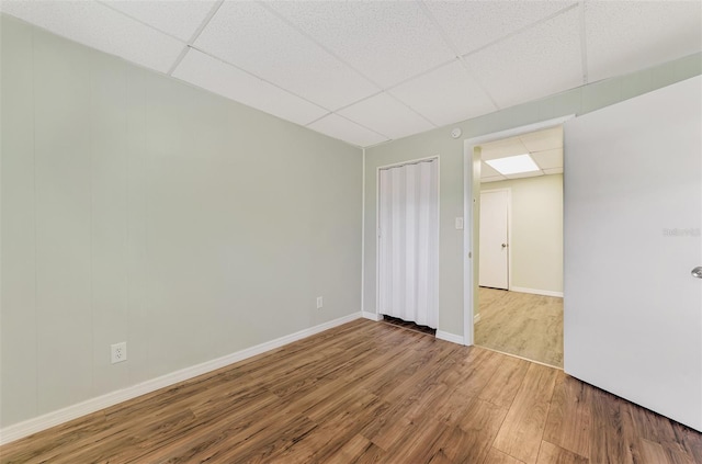 unfurnished room featuring wood-type flooring and a paneled ceiling