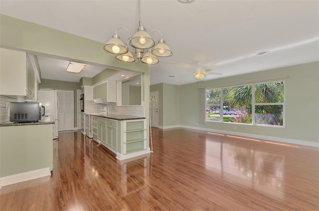 kitchen featuring white cabinets, tasteful backsplash, ceiling fan with notable chandelier, and pendant lighting