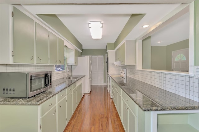 kitchen featuring backsplash, light hardwood / wood-style flooring, stone countertops, sink, and stainless steel appliances