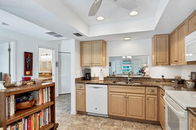 kitchen featuring ceiling fan, sink, white appliances, a tray ceiling, and dark stone countertops