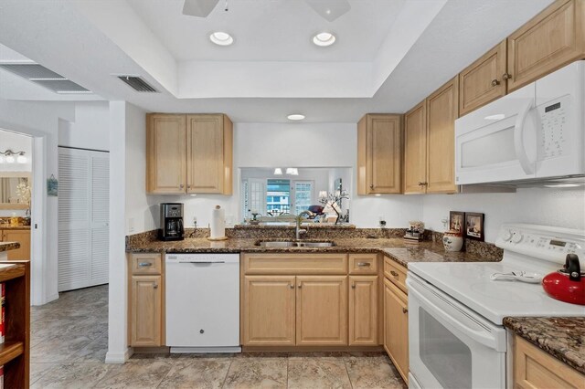 kitchen with white appliances, a tray ceiling, sink, and light brown cabinets