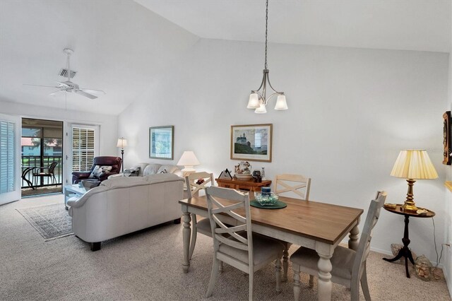 carpeted dining room with ceiling fan with notable chandelier and high vaulted ceiling