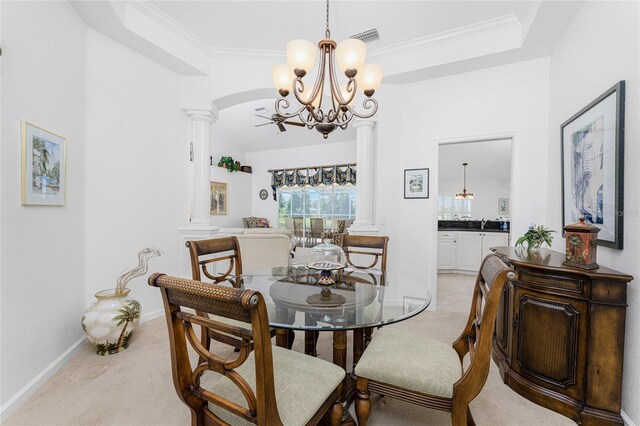 dining space featuring a raised ceiling, ornamental molding, decorative columns, light colored carpet, and an inviting chandelier