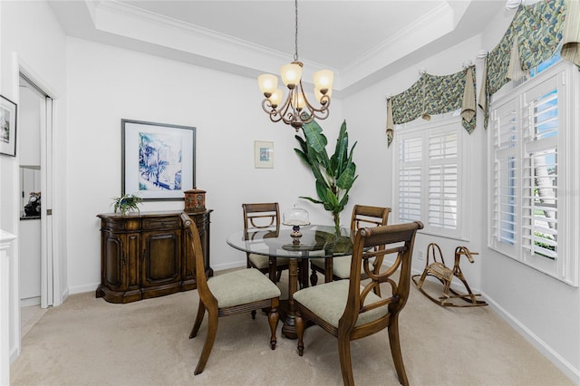 dining space featuring ornamental molding, a tray ceiling, light carpet, and a chandelier