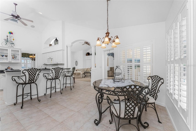 tiled dining area featuring ceiling fan with notable chandelier, decorative columns, and lofted ceiling