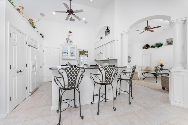 kitchen featuring ceiling fan, decorative columns, kitchen peninsula, and white cabinetry