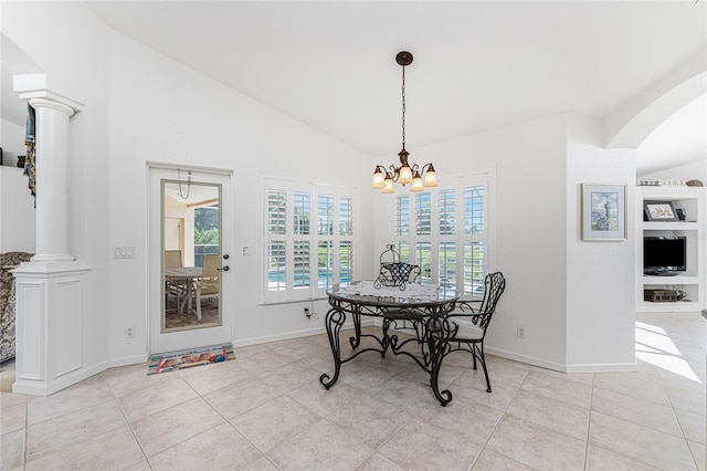 tiled dining area featuring decorative columns, a chandelier, and vaulted ceiling