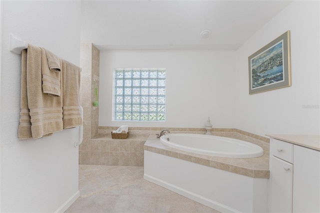 bathroom featuring tiled tub, vanity, and tile patterned flooring