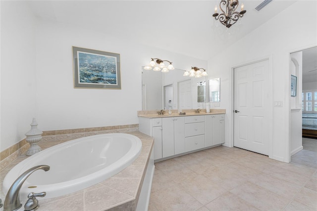 bathroom with tiled tub, vanity, vaulted ceiling, and tile patterned floors