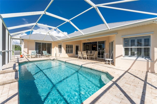 view of pool with glass enclosure and a patio area