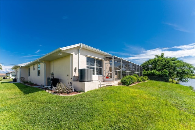 back of property featuring a lawn, central air condition unit, and glass enclosure