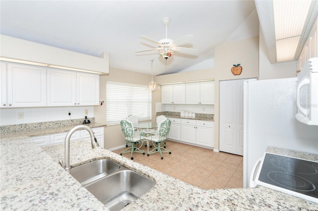 kitchen featuring sink, white cabinets, vaulted ceiling, light stone countertops, and ceiling fan