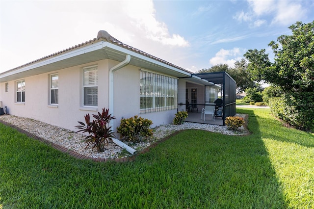 view of side of property featuring a lawn, a patio, and a lanai