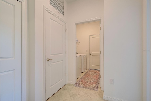 hallway with light tile patterned flooring and independent washer and dryer