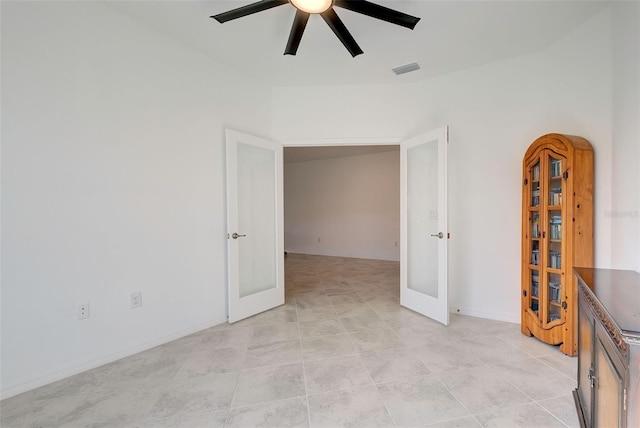 tiled empty room featuring ceiling fan and french doors