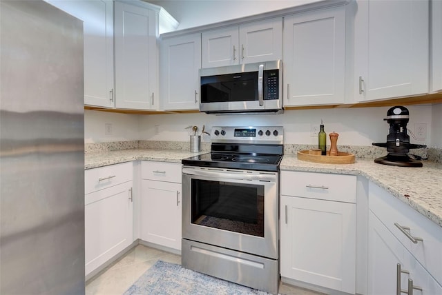 kitchen with white cabinetry, appliances with stainless steel finishes, light stone counters, and light tile patterned flooring