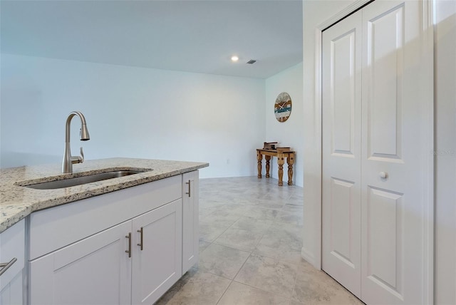 kitchen featuring white cabinets, light tile patterned flooring, light stone countertops, and sink