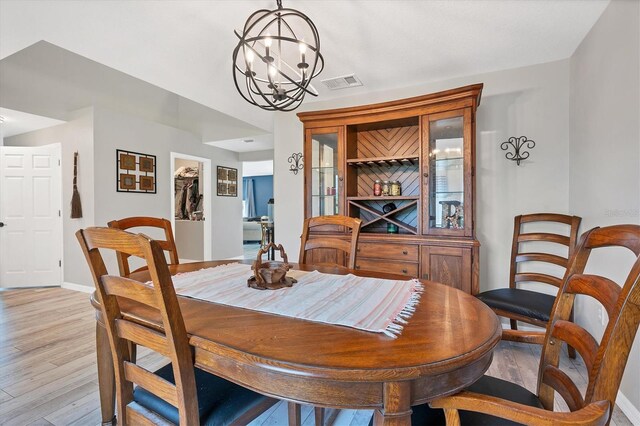 dining room with light hardwood / wood-style flooring and a chandelier