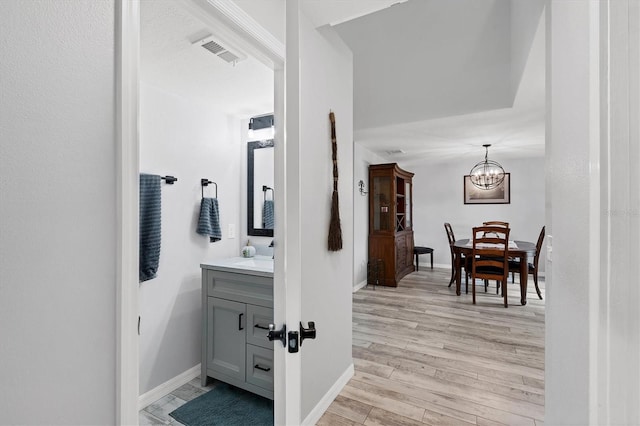 bathroom featuring wood-type flooring, vanity, and an inviting chandelier