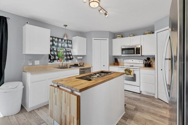 kitchen featuring pendant lighting, appliances with stainless steel finishes, light hardwood / wood-style floors, and white cabinetry