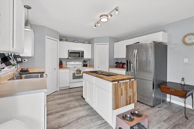13401 Galveston Ave, Port Charlotte, FL 33981 - kitchen featuring stainless steel appliances, a center island, a sink, white cabinetry, and light wood-style floors