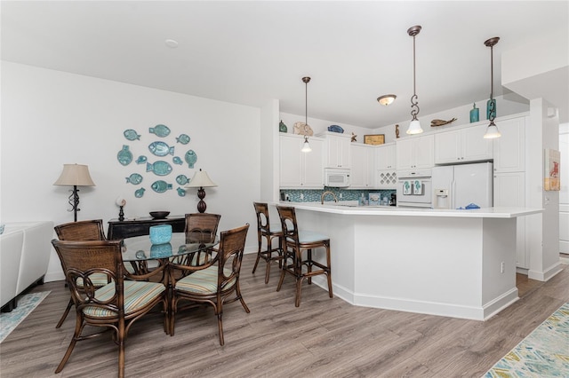 11100 Hacienda Del Mar Blvd Unit 202, Placida, FL 33946 - kitchen with backsplash, white cabinetry, a peninsula, white appliances, and light wood-style floors