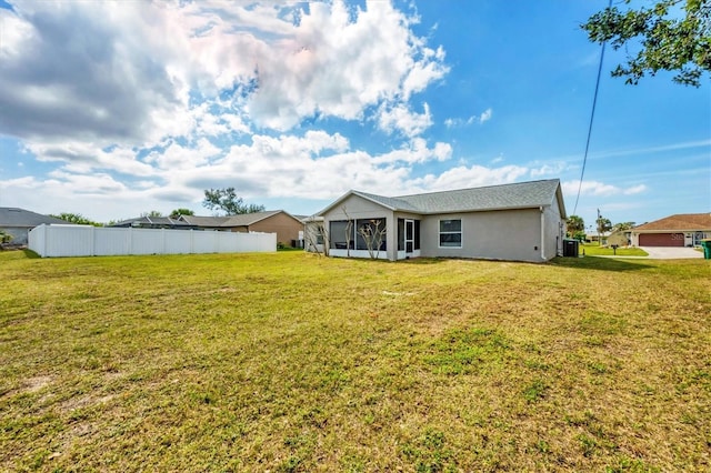 back of property featuring a sunroom, fence, and a lawn