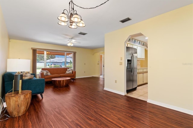 living room featuring ceiling fan with notable chandelier and light hardwood / wood-style flooring