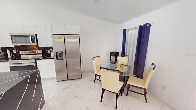 kitchen with white cabinets, appliances with stainless steel finishes, and vaulted ceiling