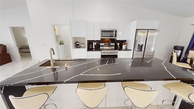 kitchen featuring white cabinets, sink, stainless steel appliances, and vaulted ceiling