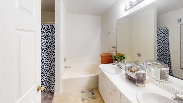 bathroom featuring tiled tub, vanity, a textured ceiling, and tile patterned floors