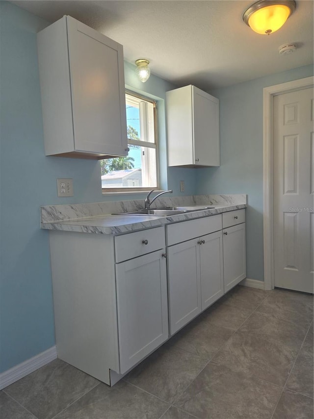 kitchen with white cabinetry, sink, and dark tile patterned floors