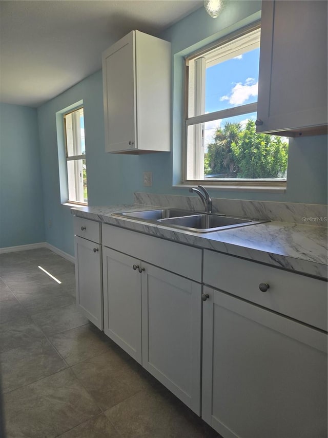 kitchen featuring dark tile patterned flooring, sink, and white cabinets