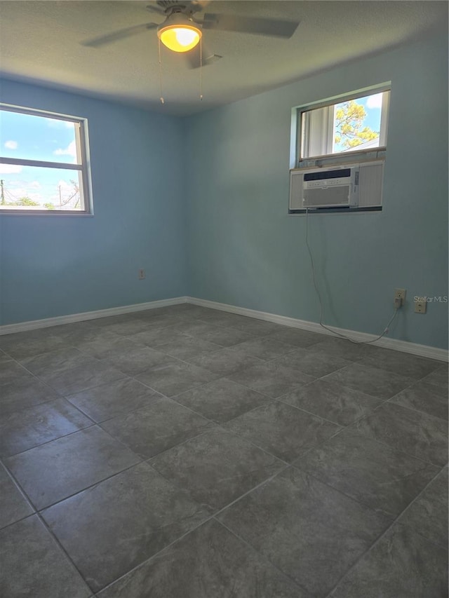 spare room featuring ceiling fan, cooling unit, and a wealth of natural light