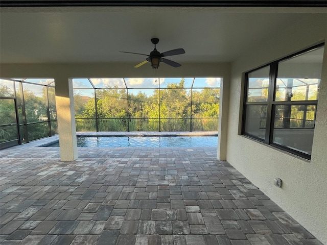 view of swimming pool featuring ceiling fan, glass enclosure, and a patio area