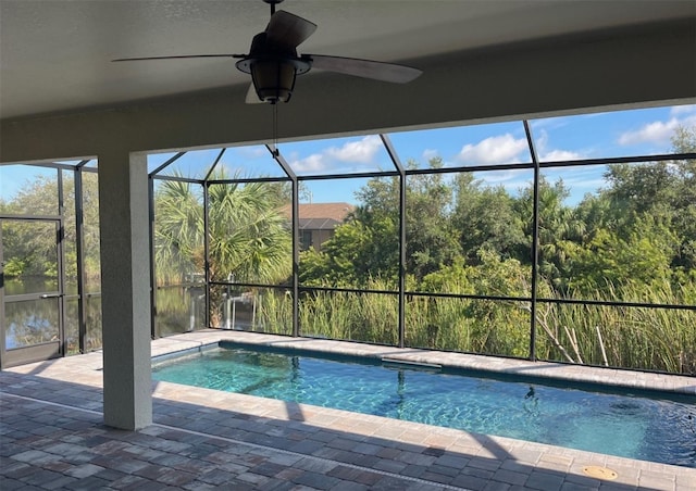 outdoor pool with a patio, glass enclosure, and ceiling fan
