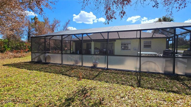 back of property featuring a pool, a lawn, and glass enclosure