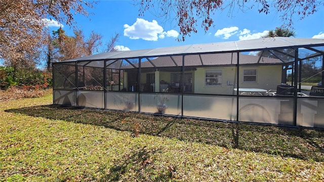 back of house featuring a lawn and glass enclosure