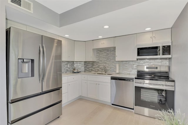 kitchen with white cabinets, stainless steel appliances, sink, and tasteful backsplash