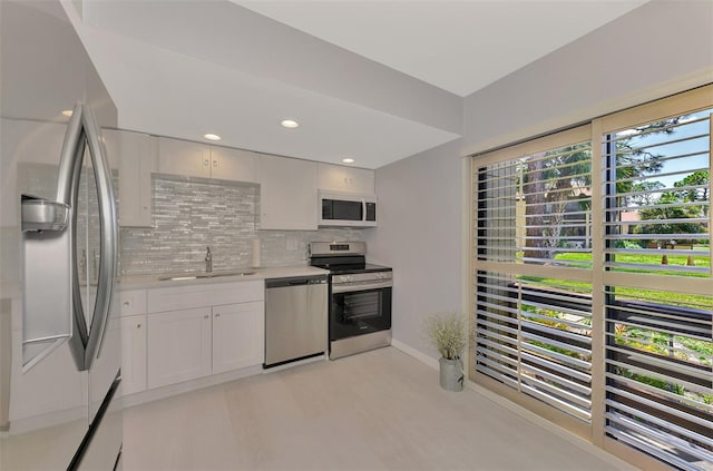 kitchen featuring light wood-type flooring, sink, white cabinets, decorative backsplash, and stainless steel appliances