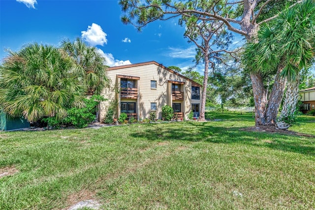 rear view of property featuring a balcony and a yard