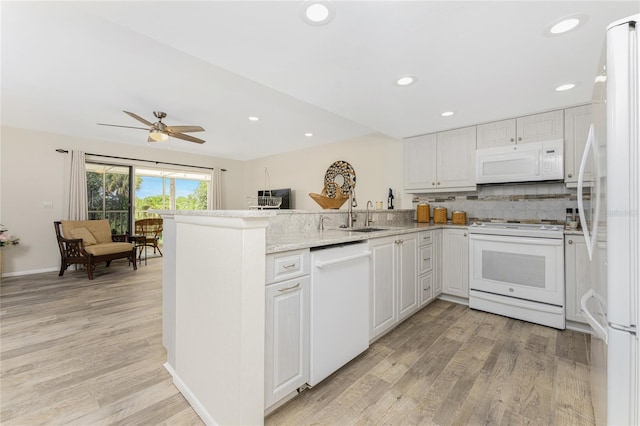 kitchen featuring white appliances, sink, kitchen peninsula, light wood-type flooring, and white cabinetry