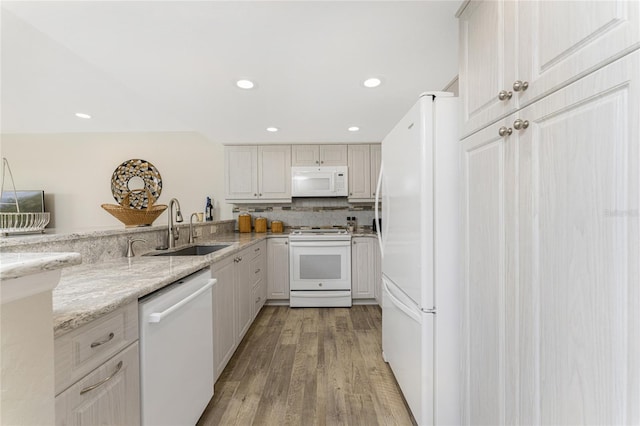 kitchen featuring light stone countertops, backsplash, white appliances, sink, and light hardwood / wood-style floors