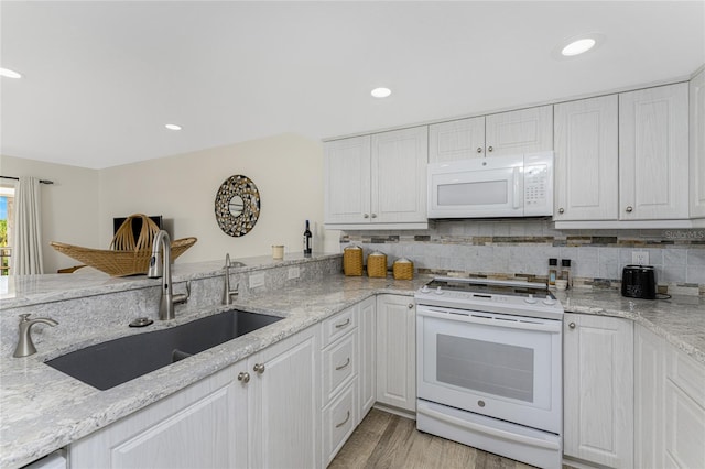 kitchen featuring white cabinets, light stone counters, white appliances, and sink