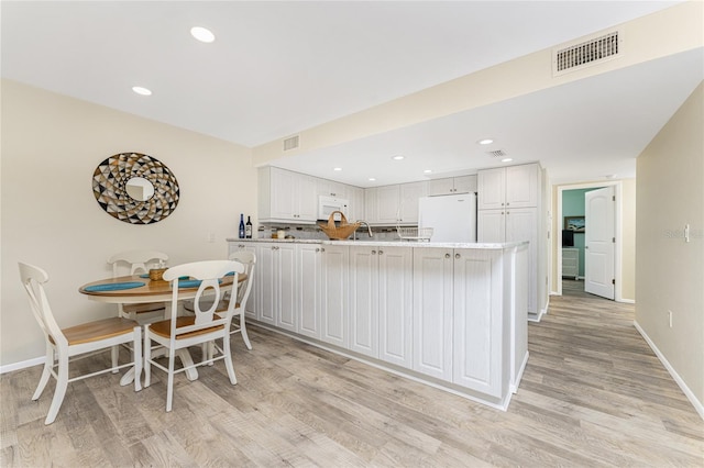 kitchen featuring white cabinets, white appliances, kitchen peninsula, and light hardwood / wood-style floors