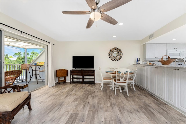 dining space with ceiling fan and light hardwood / wood-style flooring