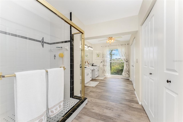 bathroom featuring ceiling fan, vanity, a shower with shower door, and hardwood / wood-style flooring