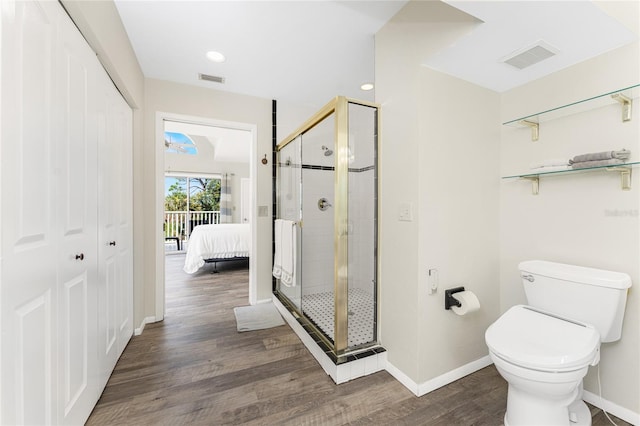 bathroom with an enclosed shower, toilet, and wood-type flooring