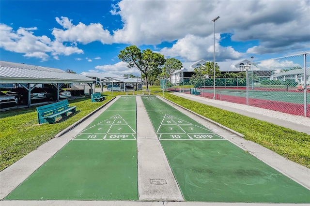 view of home's community featuring tennis court and a yard