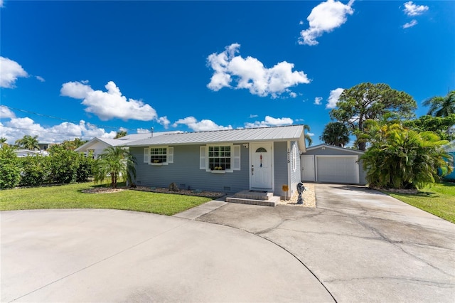 ranch-style home featuring an outbuilding, a front lawn, concrete driveway, a detached garage, and metal roof